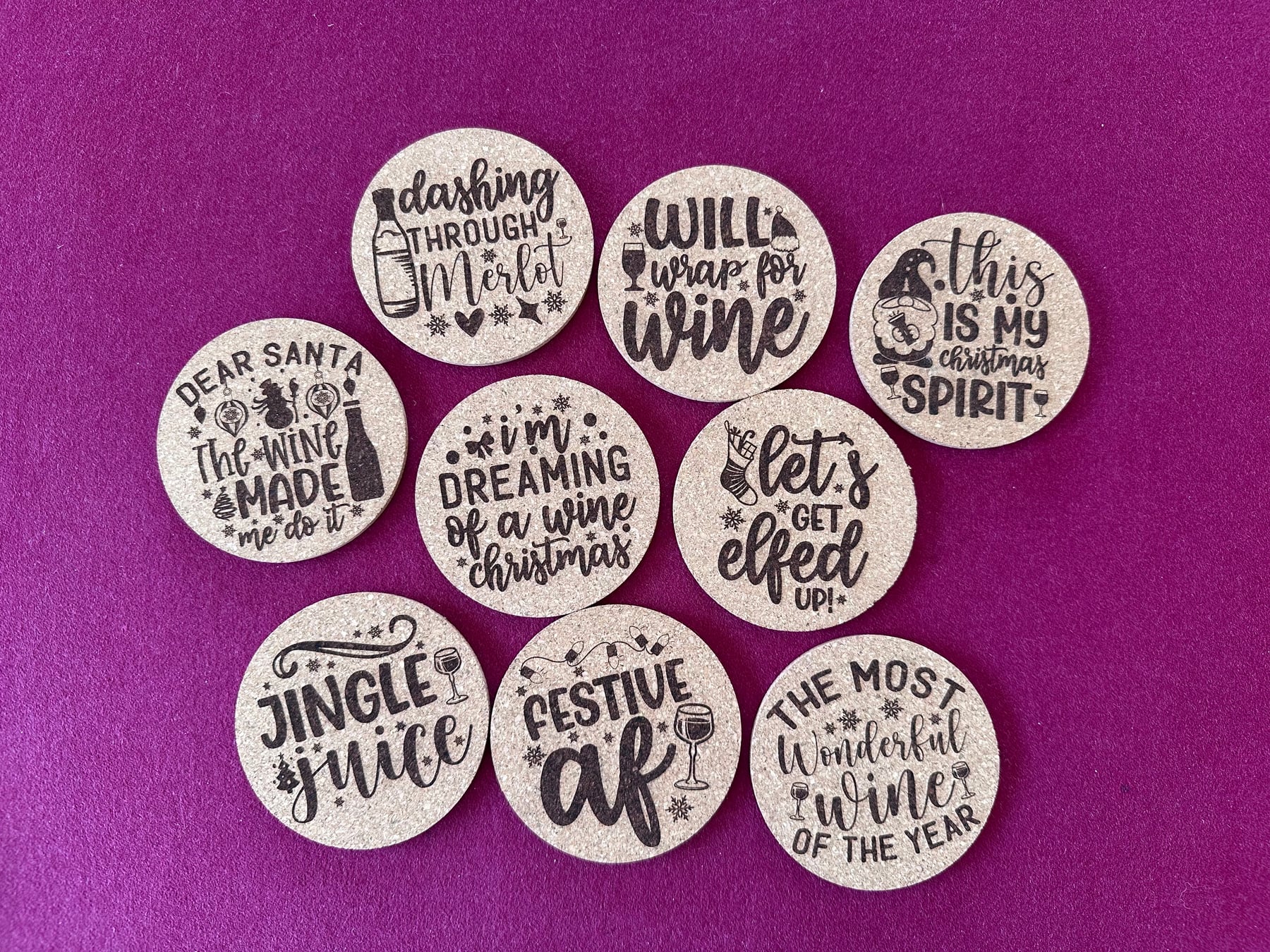 Nine cork coasters engraved with playful wine-themed Christmas sayings