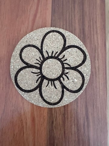 Round cork coaster engraved with a large flower