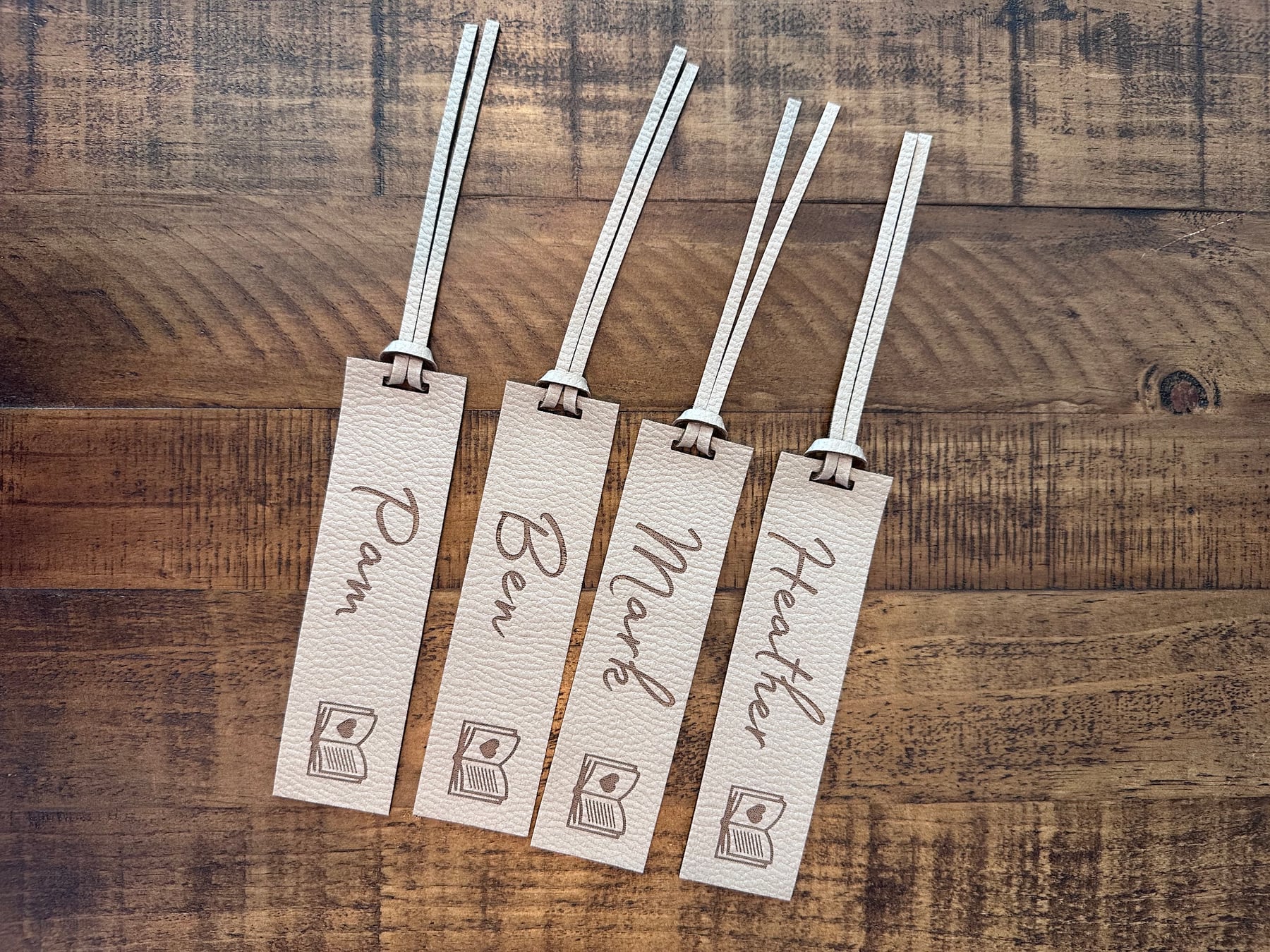 Four white faux-leather bookmarks personalised with family names