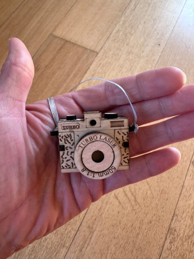 Tiny three-dimensional wooden camera held in a hand