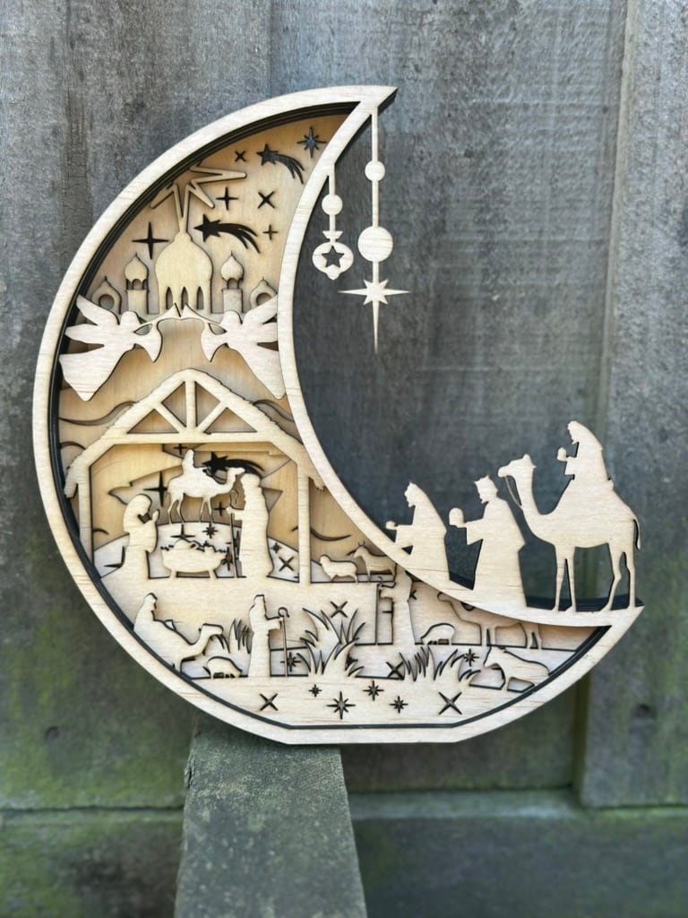 Intricate layered wooden nativity scene in a crescent moon